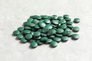 Photo of Heap of green spirulina pills on light table