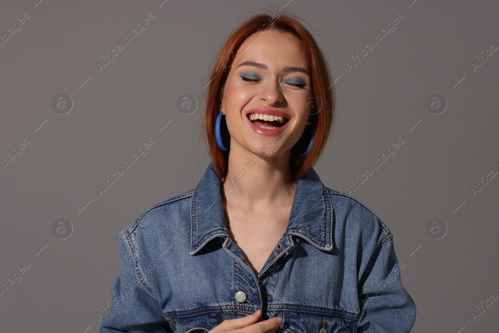 Photo of Beautiful young woman in denim jacket on gray background