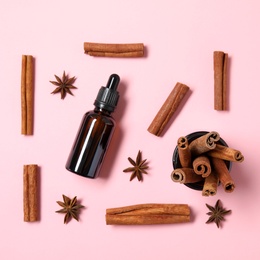 Photo of Flat lay composition with cinnamon essential oil on pink background