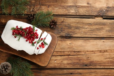 Photo of Traditional classic Christmas cake decorated with cranberries, pomegranate seeds and rosemary on wooden table, flat lay. Space for text