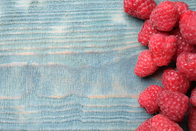 Photo of Delicious fresh ripe raspberries on blue wooden table, top view. Space for text