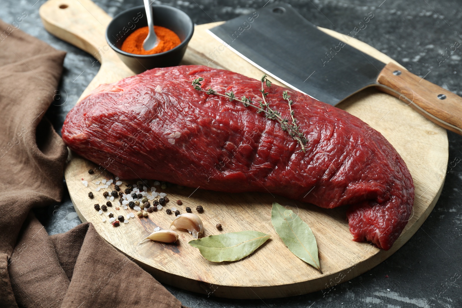 Photo of Piece of raw beef meat, knife and spices on black textured table, closeup