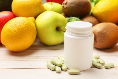 Dietary supplements. Bottle and pills near food products on light wooden table, closeup