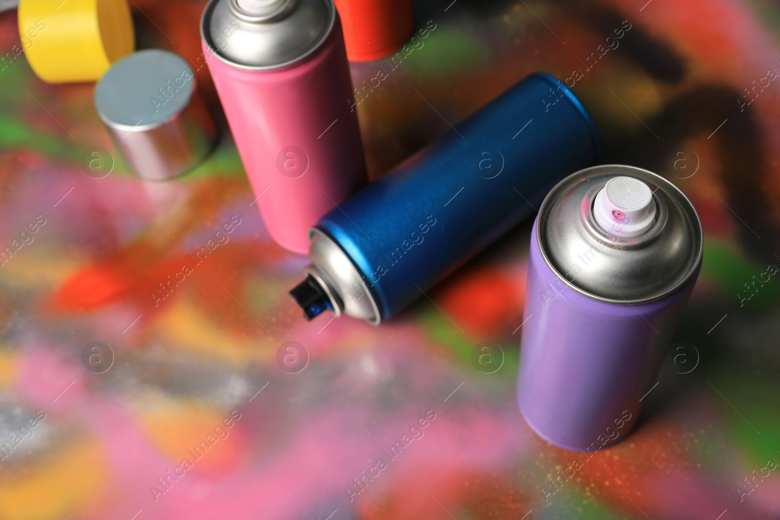 Photo of Cans of different graffiti spray paints on color background, above view