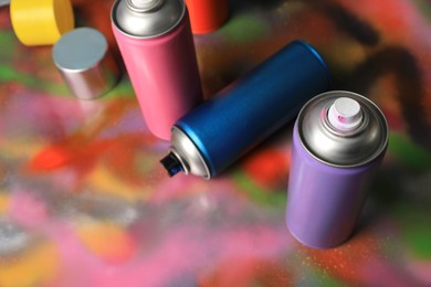 Cans of different graffiti spray paints on color background, above view
