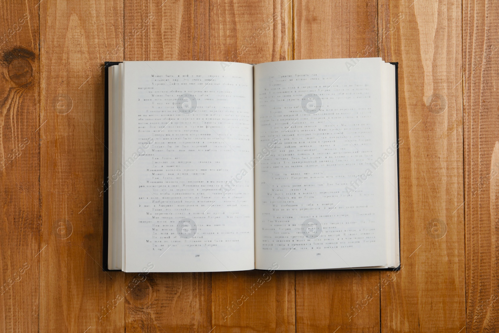 Photo of Open old hardcover book on wooden table, top view