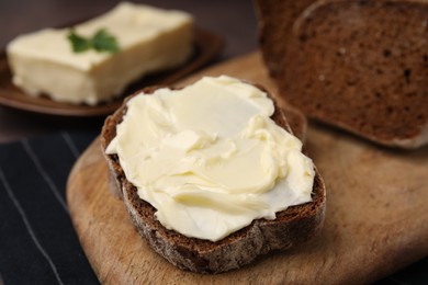 Photo of Slices of tasty bread with butter on wooden board, closeup