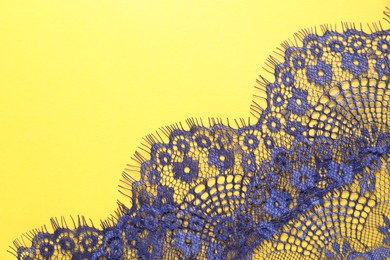 Blue lace on yellow background, top view. Space for text