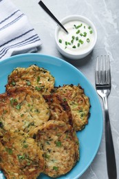 Photo of Delicious zucchini pancakes served on grey table, flat lay