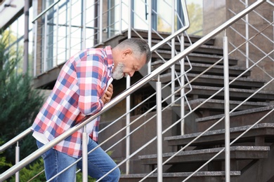 Mature man having heart attack on stairs, outdoors