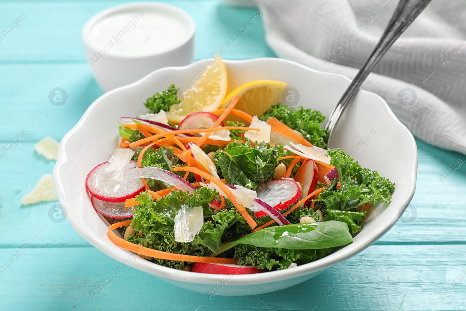 Photo of Tasty fresh kale salad on light blue wooden table, closeup