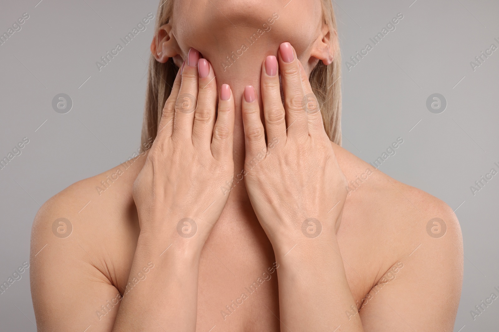 Photo of Woman touching her neck on grey background, closeup