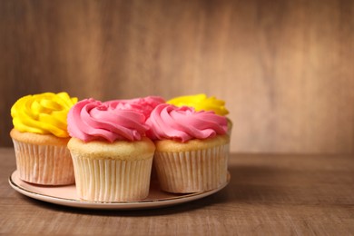 Photo of Delicious cupcakes with bright cream on wooden table, closeup. Space for text