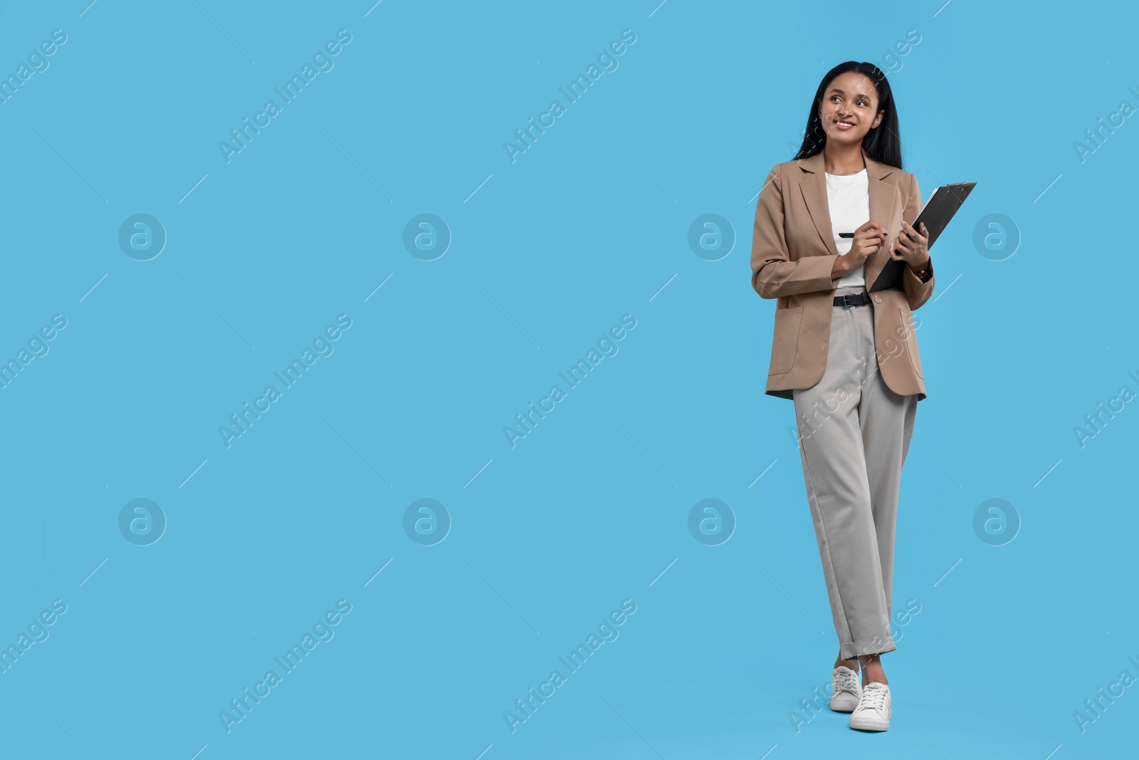 Photo of Beautiful secretary with clipboard and pen on light blue background, space for text
