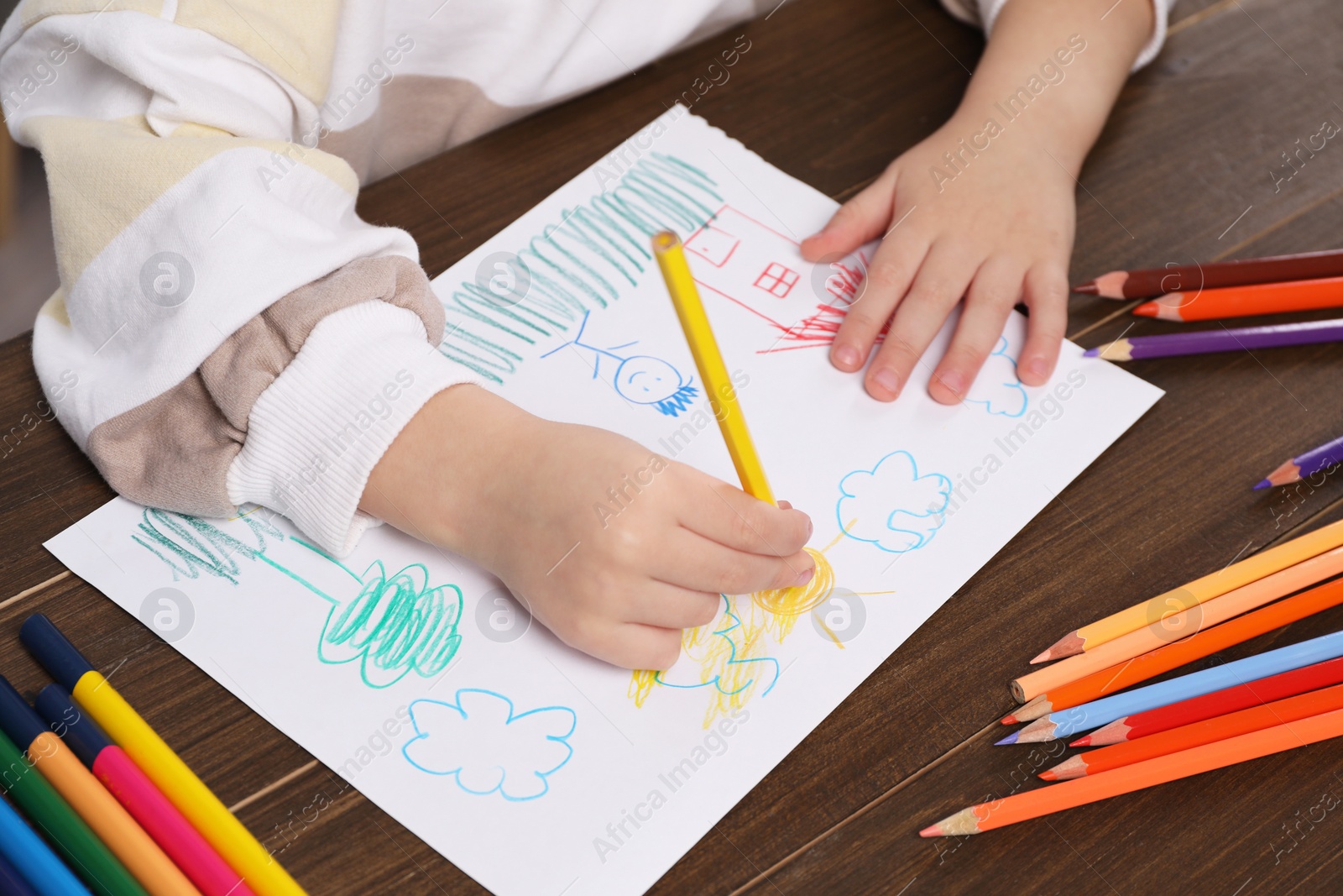 Photo of Little boy drawing with pencil at wooden table, closeup. Child`s art