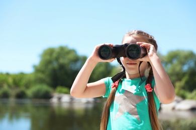 Little girl with binoculars outdoors. Summer camp