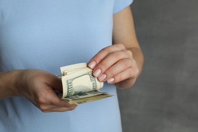 Money exchange. Woman counting dollar banknotes on grey background, closeup