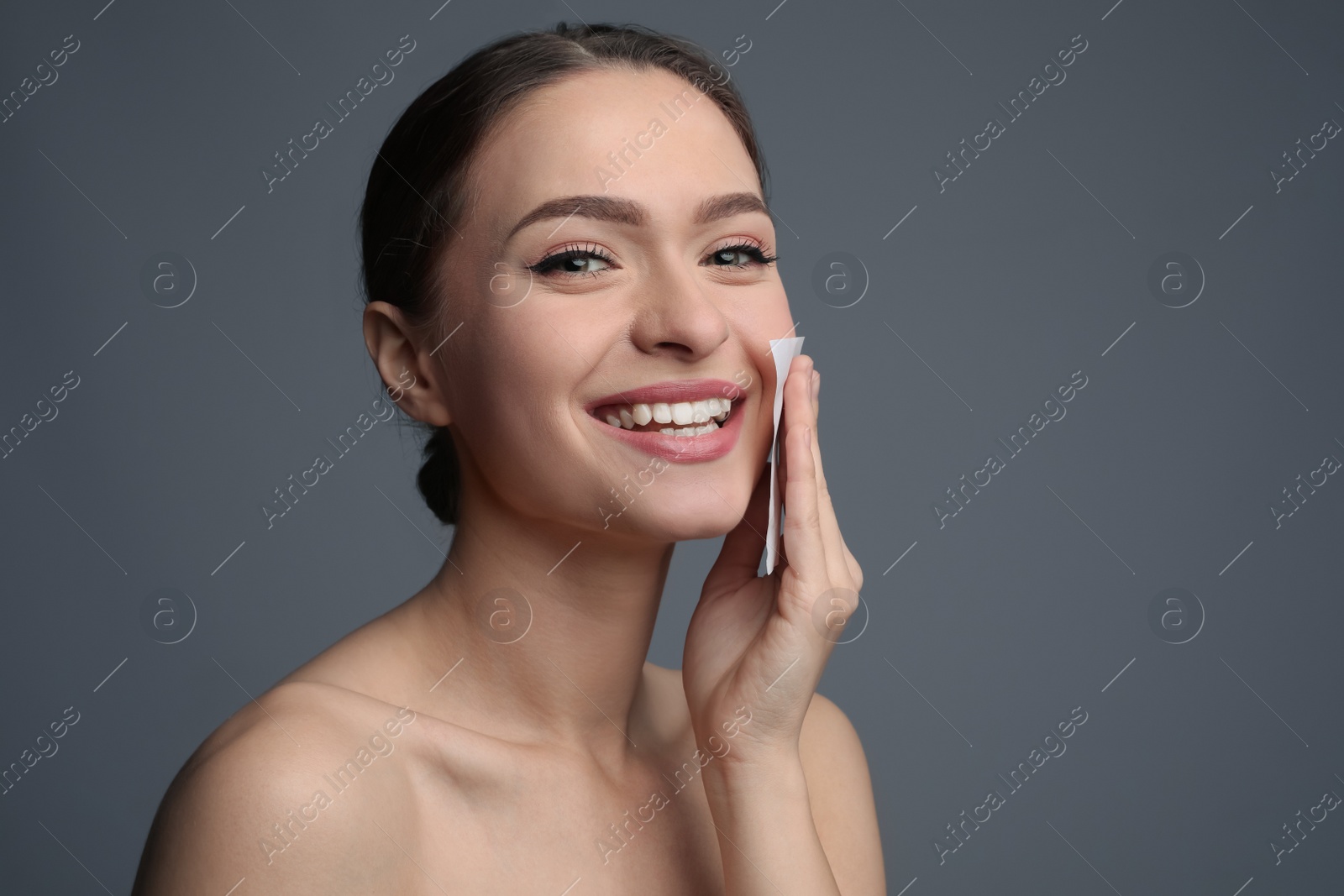 Photo of Beautiful woman using mattifying wipe on grey background