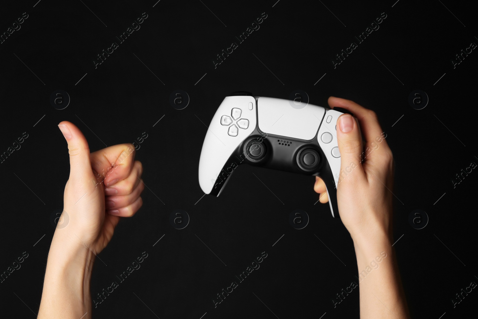 Photo of Woman with game controller showing thumbs up on black background, closeup