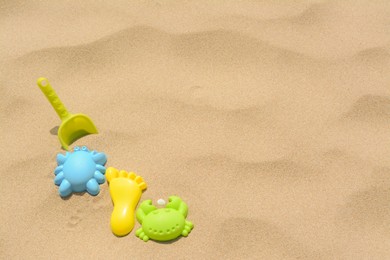 Photo of Set of colorful beach toys on sand. Space for text