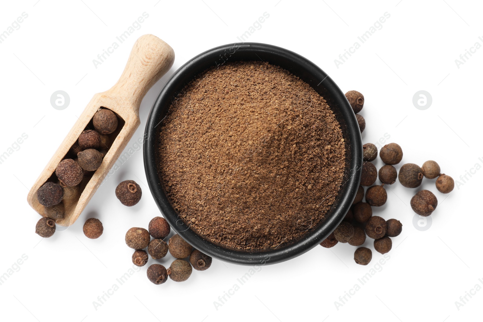 Photo of Ground allspice pepper in bowl, grains and scoop isolated on white, top view