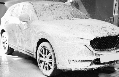 Photo of Worker cleaning automobile with high pressure water jet at car wash