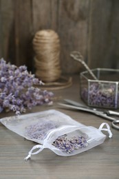 Photo of Scented sachet with dried lavender flowers on wooden table
