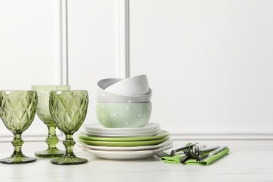 Photo of Beautiful ceramic dishware, glasses and cutlery on white marble table. Space for text