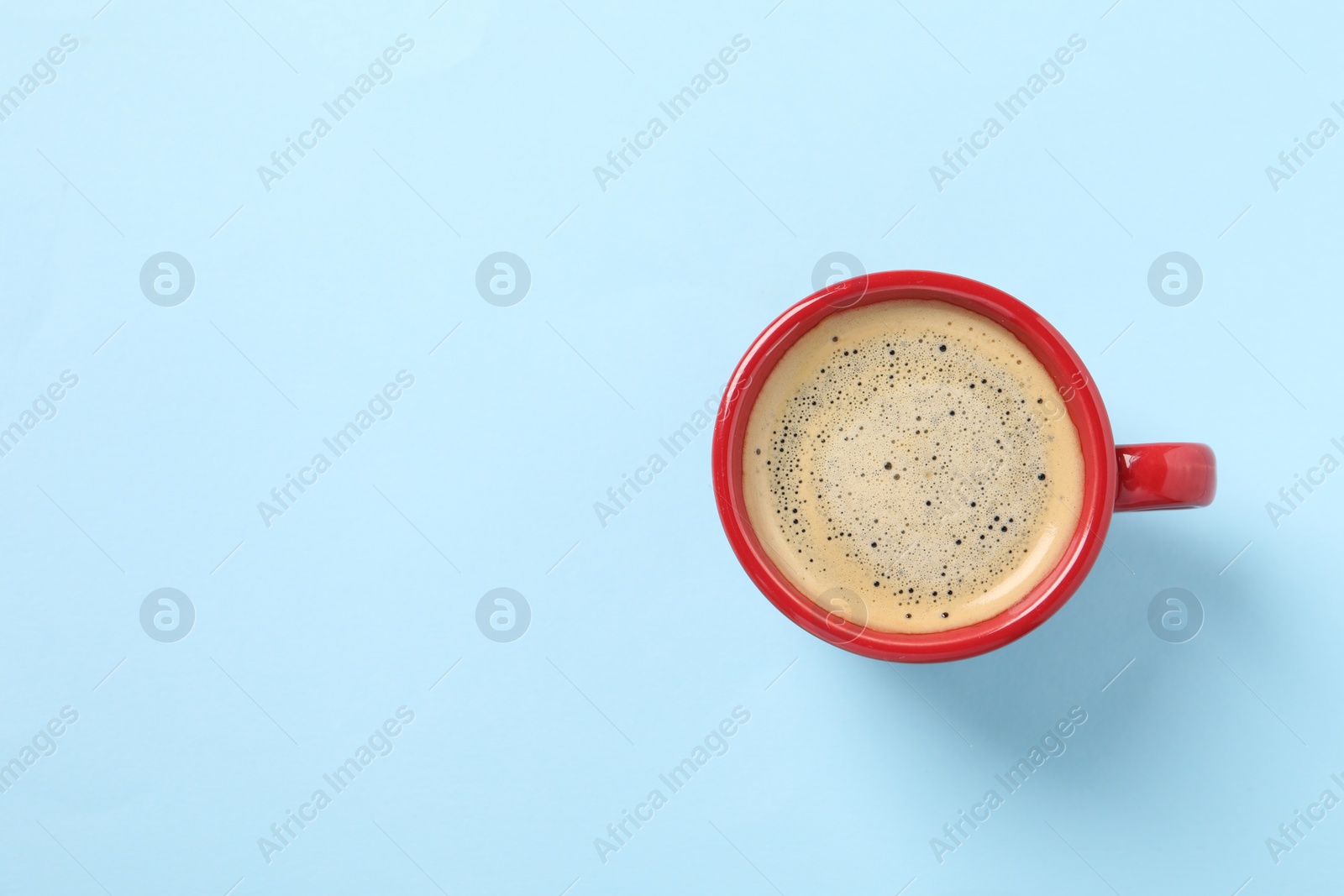 Photo of Tasty coffee in cup on light blue background, top view. Space for text