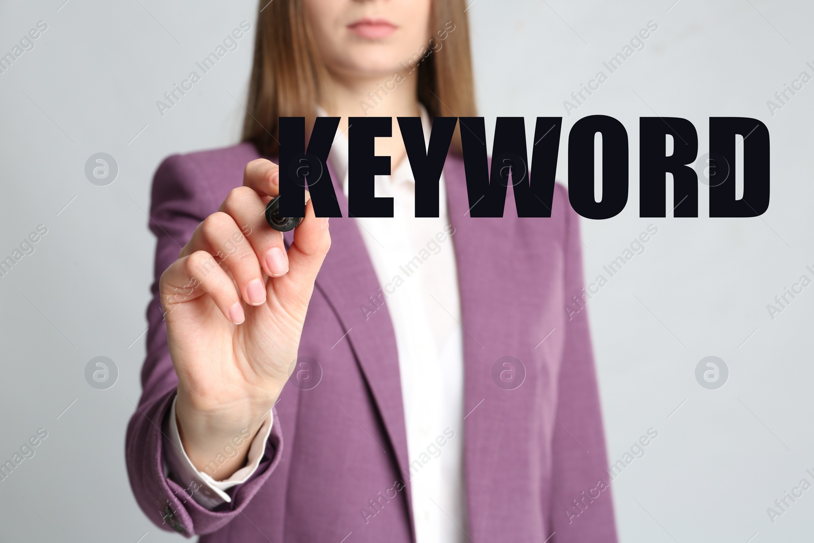 Image of Woman writing word KEYWORD on transparent board against grey background, closeup