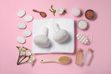 Flat lay composition with herbal massage bags and other spa products on pink background