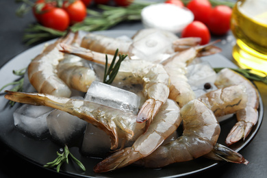 Photo of Fresh raw shrimps with rosemary and ice cubes on plate, closeup