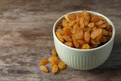 Bowl with raisins and space for text on wooden background. Dried fruit as healthy snack