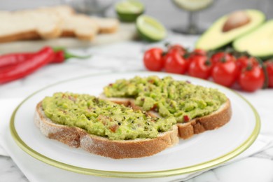 Photo of Delicious sandwiches with guacamole and ingredients on white table, closeup