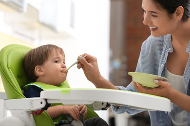 Young nanny feeding cute little baby at home