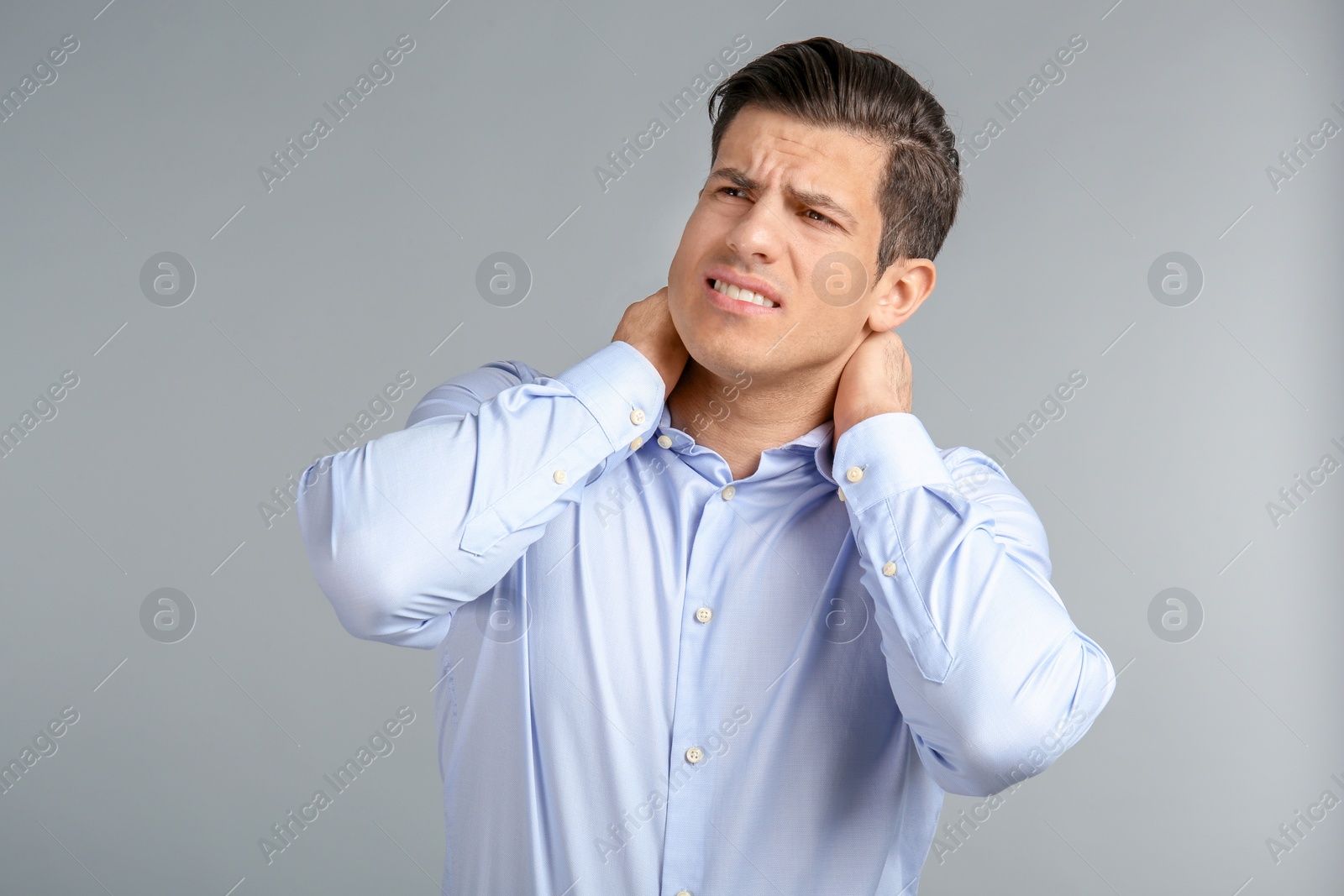 Photo of Young man suffering from neck pain on grey background