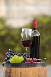 Delicious wine and ripe grapes on wooden barrel outdoors