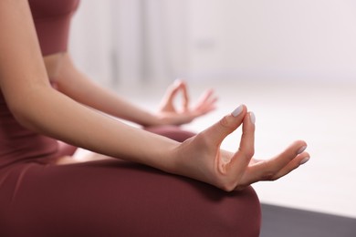 Photo of Woman in sportswear meditating indoors, closeup view