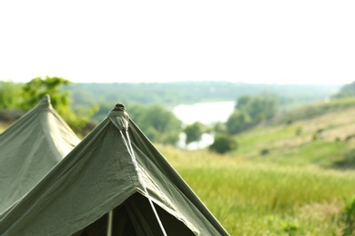 Photo of Camping tent in green field on sunny day. Space for text