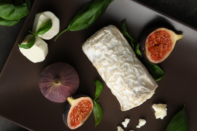Photo of Delicious goat cheese with figs and basil on plate, flat lay