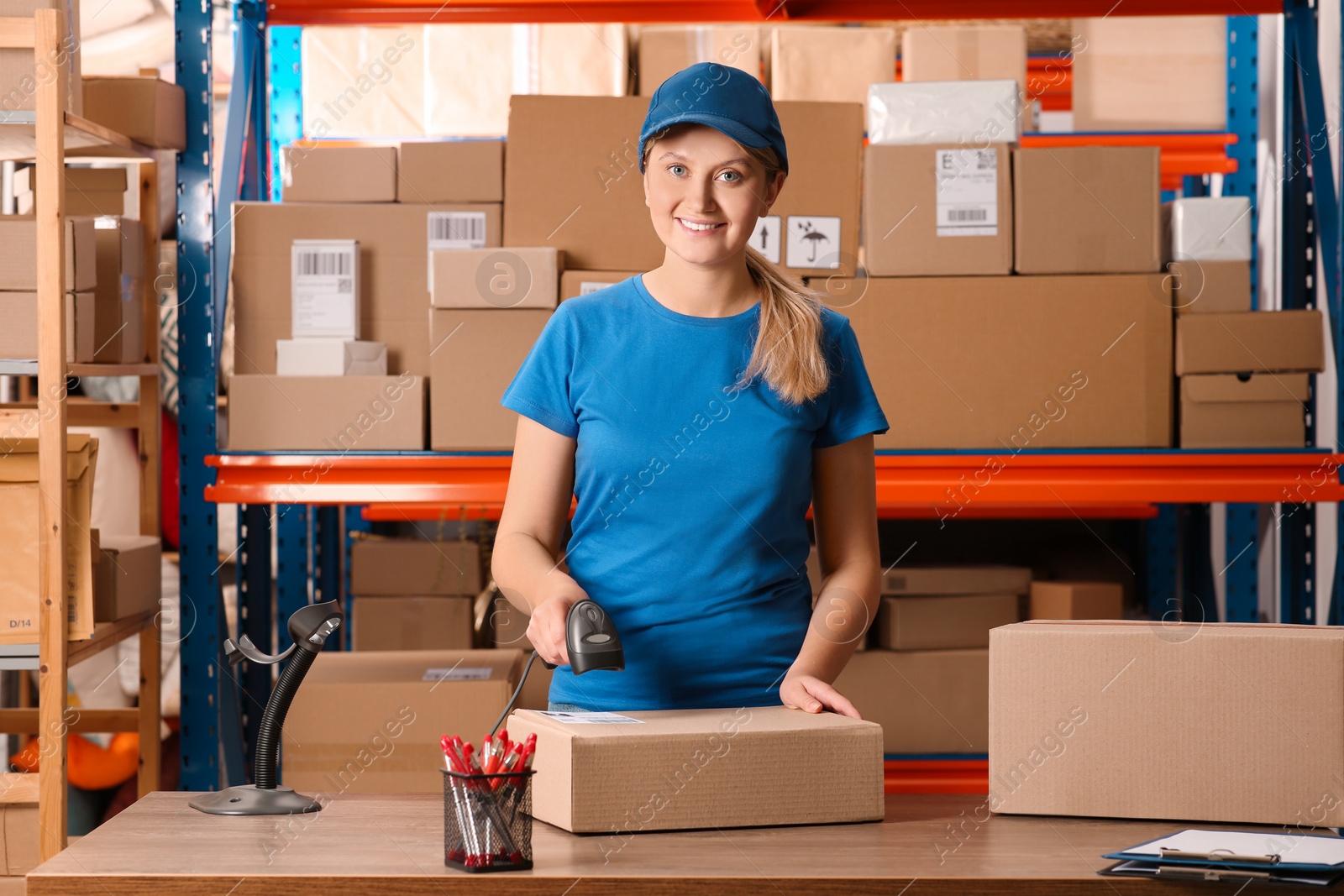 Photo of Post office worker with scanner reading parcel barcode at counter