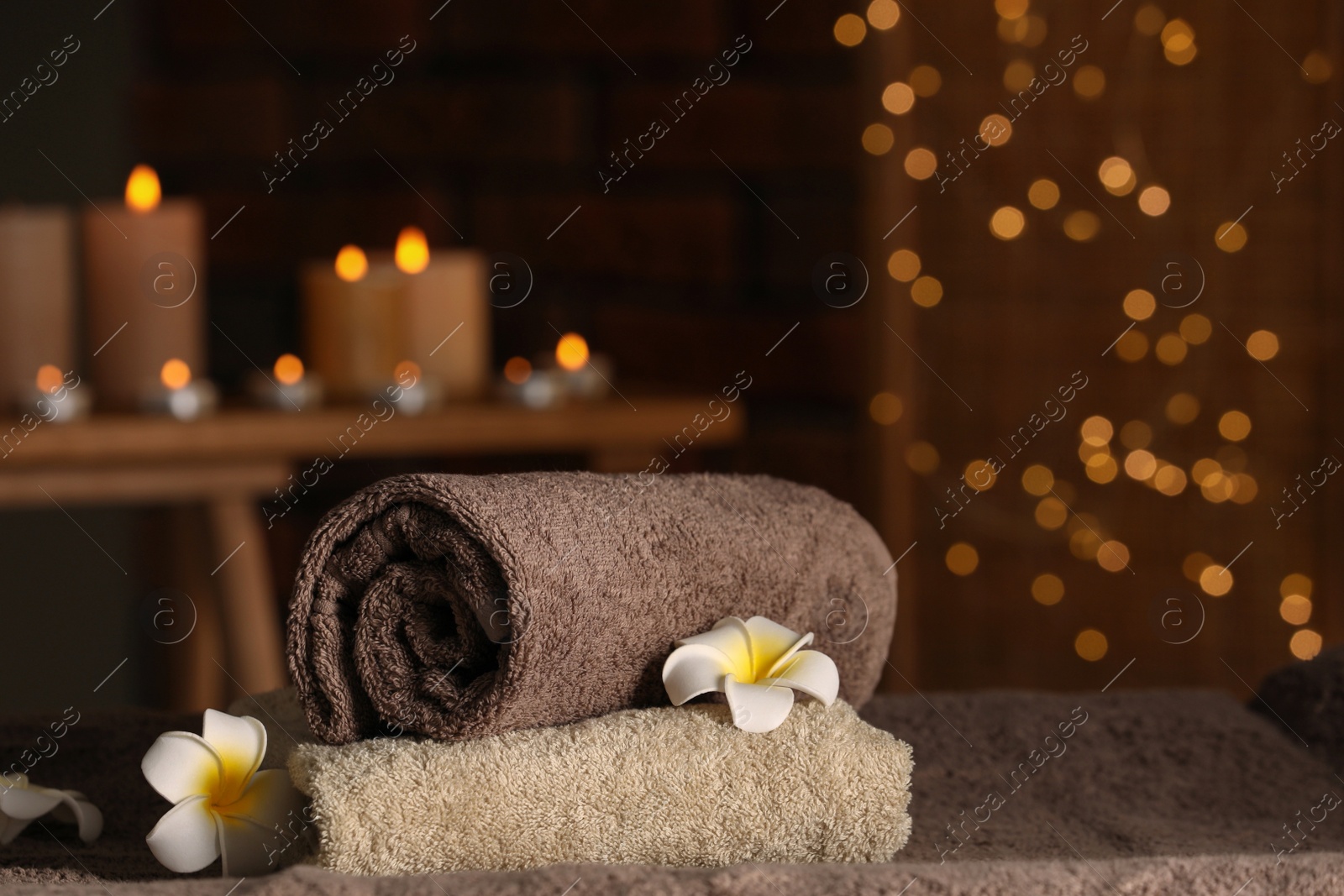 Photo of Spa composition with towels and plumeria flowers on massage table in wellness center