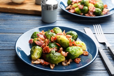 Photo of Tasty roasted Brussels sprouts with bacon on blue wooden table