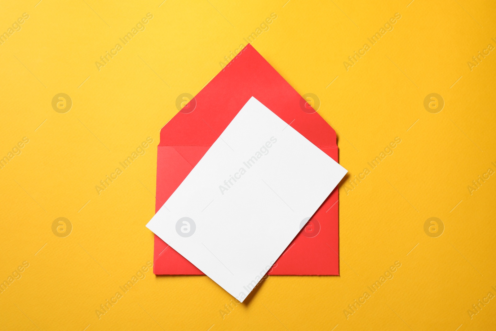 Photo of Blank sheet of paper and letter envelope on orange background, top view