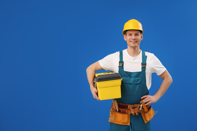 Photo of Handsome carpenter with tool box on blue background. Space for text