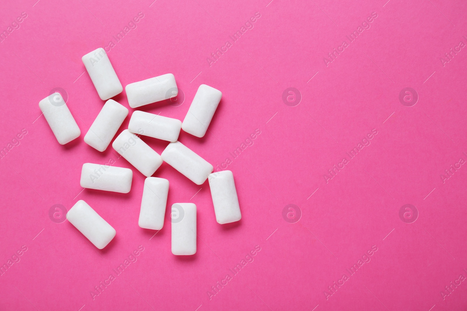 Photo of Tasty white chewing gums on pink background, flat lay. Space for text