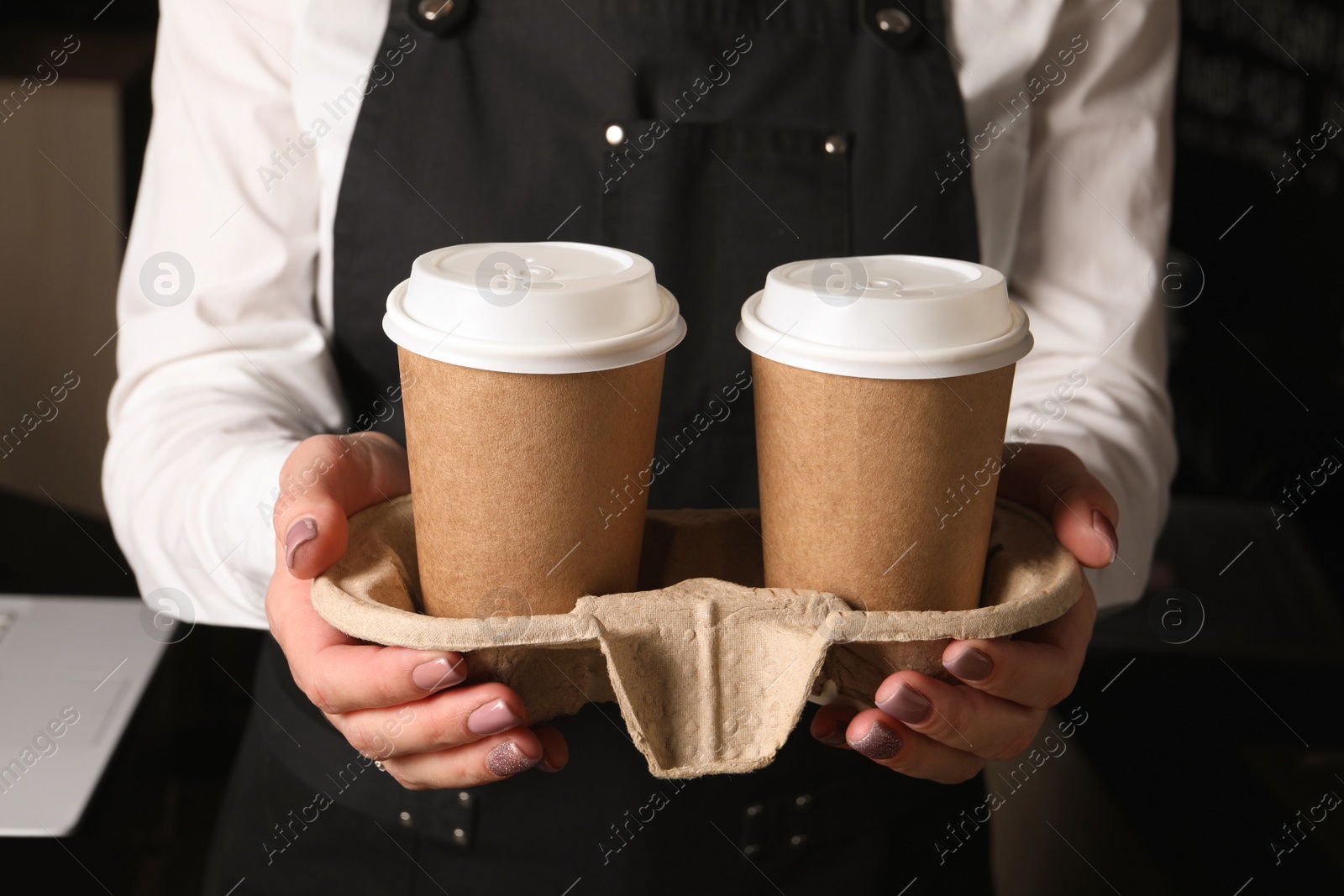 Photo of Barista holding takeaway paper cups with coffee in cafe, closeup