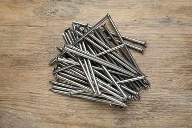 Many metal nails on wooden background, flat lay