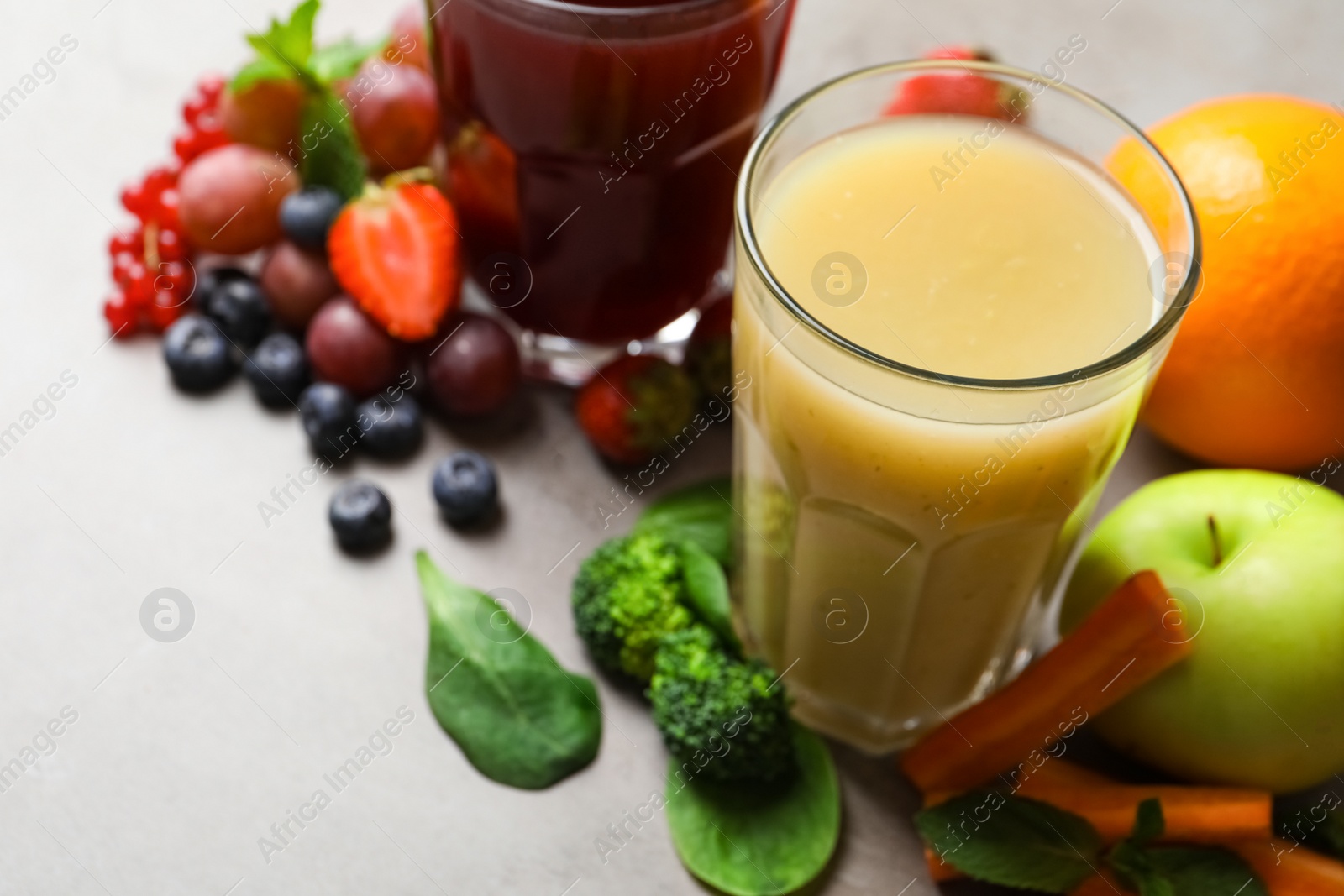 Photo of Delicious juice and fresh ingredients on grey table, closeup. Space for text