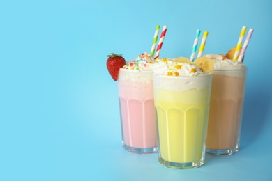 Glasses of tasty milk shakes and space for text on color background